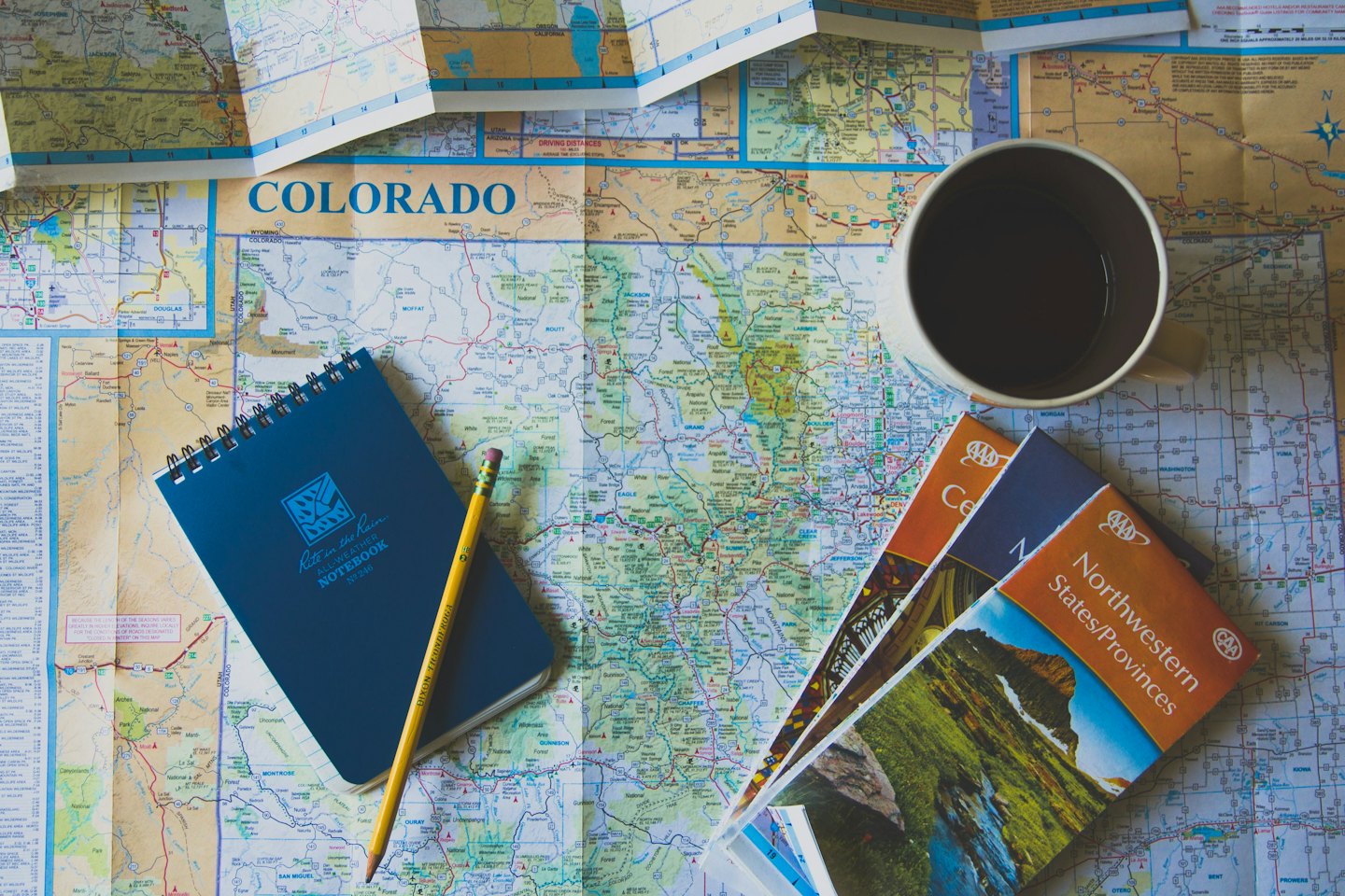 Colorado map with travel planning notebook, pencil, and mug.