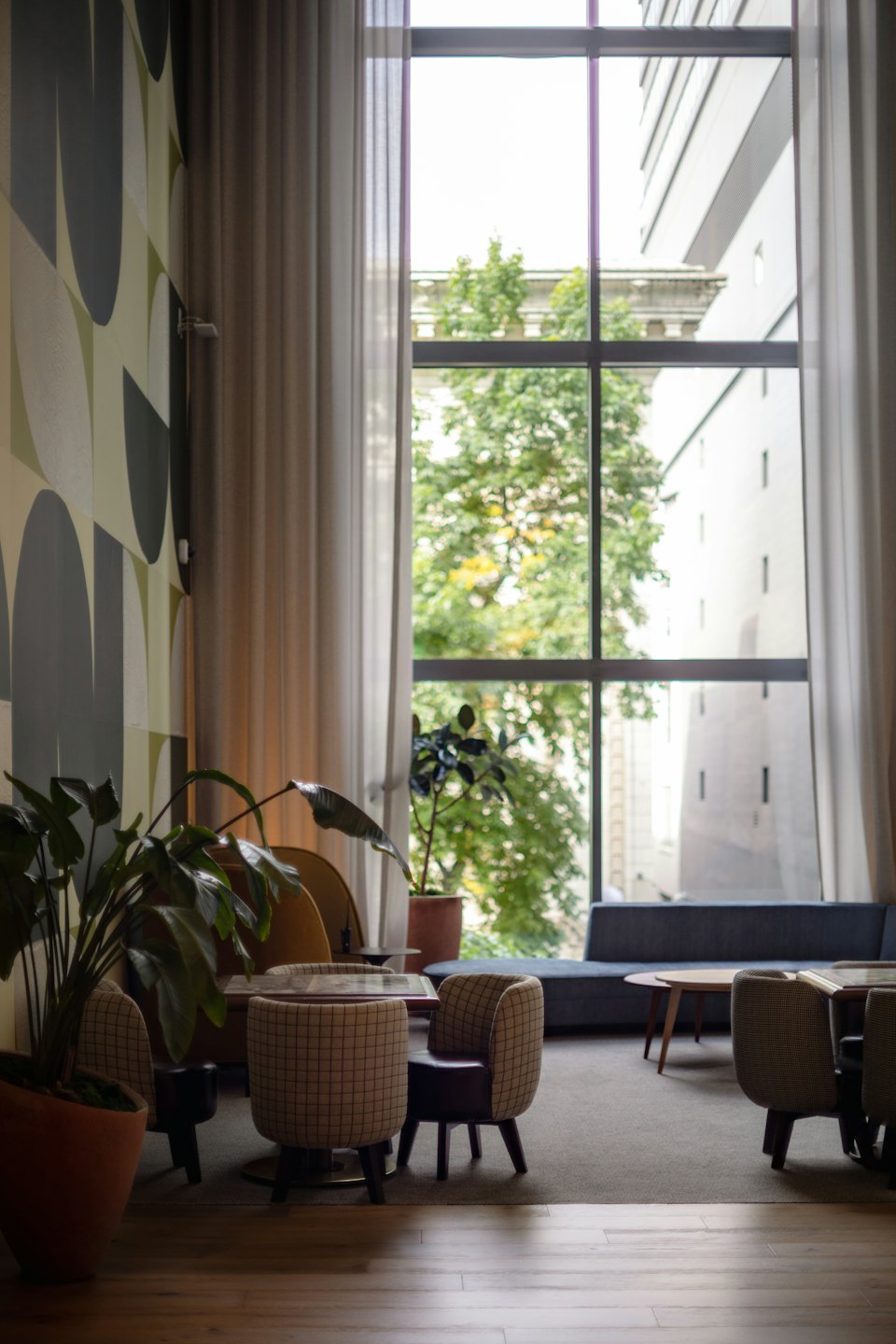Hotel lobby lounge with checkered armchairs and blue sofa near window.